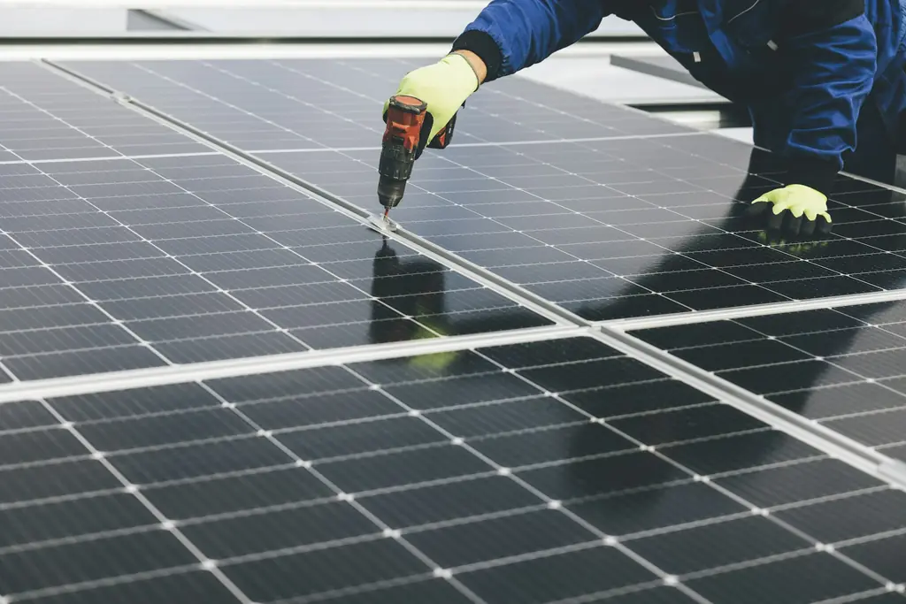Installer in gloves fixing solar panels in place with a drill